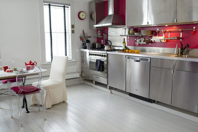 Imagen de cocina comedor lineal ecléctica de tamaño medio con armarios con paneles lisos, salpicadero rojo, electrodomésticos de acero inoxidable, suelo de madera pintada y suelo gris