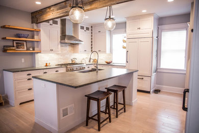 Inspiration for a mid-sized cottage l-shaped limestone floor eat-in kitchen remodel in Philadelphia with a farmhouse sink, shaker cabinets, white cabinets, soapstone countertops, ceramic backsplash, stainless steel appliances and an island