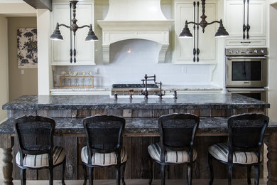 Inspiration for a mid-sized farmhouse light wood floor eat-in kitchen remodel in San Diego with a farmhouse sink, shaker cabinets, distressed cabinets, white backsplash, subway tile backsplash, stainless steel appliances, an island and granite countertops