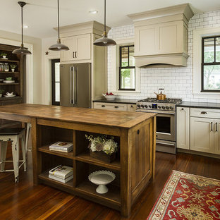 Foto di una cucina a L country con lavello stile country, ante in stile shaker, ante beige, paraspruzzi bianco, paraspruzzi con piastrelle diamantate, elettrodomestici in acciaio inossidabile, parquet scuro, isola e pavimento marrone