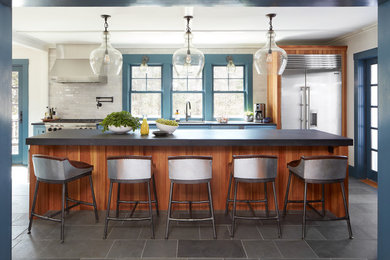 Mid-sized farmhouse single-wall slate floor and gray floor eat-in kitchen photo in Boston with a single-bowl sink, recessed-panel cabinets, blue cabinets, limestone countertops, subway tile backsplash, stainless steel appliances, an island and white backsplash
