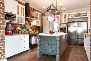 他の地域にある広いカントリー風のおしゃれなキッチン (シェーカースタイル扉のキャビネット、白いキャビネット、レンガの床、白いキッチンカウンター) の写真