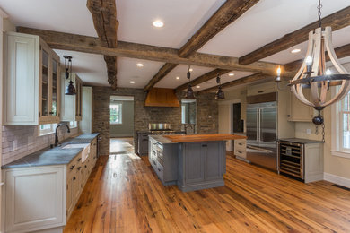 Kitchen - cottage medium tone wood floor kitchen idea in DC Metro with a farmhouse sink, recessed-panel cabinets, soapstone countertops, white backsplash, brick backsplash, stainless steel appliances and an island