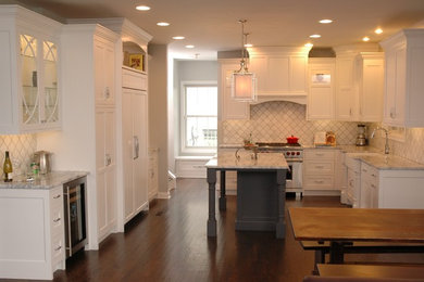 Foto de cocina de estilo de casa de campo grande con fregadero sobremueble, puertas de armario blancas, salpicadero blanco, electrodomésticos de acero inoxidable, suelo de madera oscura, una isla, encimera de mármol, salpicadero de mármol, armarios con rebordes decorativos y suelo marrón