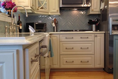 Example of a large country eat-in kitchen design in Charlotte with raised-panel cabinets, quartzite countertops, blue backsplash and an island