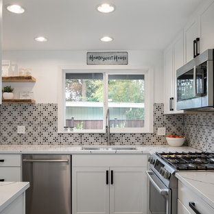 Mid-sized farmhouse enclosed kitchen photos - Enclosed kitchen - mid-sized country l-shaped enclosed kitchen idea in Seattle with an undermount sink, shaker cabinets, white cabinets, quartz countertops, gray backsplash, ceramic backsplash, stainless steel appliances, no island and white countertops