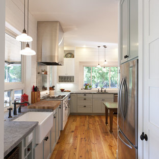 Diseño de cocina de estilo de casa de campo con electrodomésticos de acero inoxidable, fregadero sobremueble y encimera de esteatita