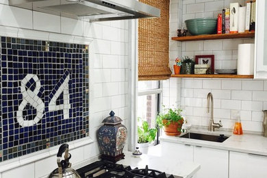 Inspiration for a mid-sized contemporary l-shaped medium tone wood floor and brown floor eat-in kitchen remodel in New York with an undermount sink, flat-panel cabinets, white cabinets, white backsplash, subway tile backsplash, stainless steel appliances, white countertops, marble countertops and no island
