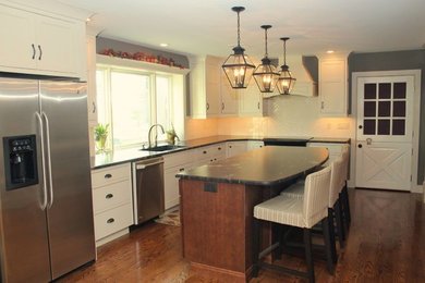 Example of a mid-sized farmhouse l-shaped medium tone wood floor and beige floor enclosed kitchen design in Philadelphia with an undermount sink, shaker cabinets, white cabinets, granite countertops, white backsplash, subway tile backsplash, stainless steel appliances and an island