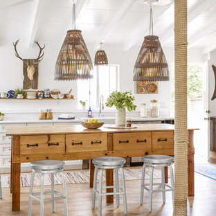 Small farmhouse kitchen designs - Small cottage light wood floor kitchen photo in Los Angeles with a farmhouse sink, white cabinets, quartz countertops, white backsplash, stainless steel appliances, an island and shaker cabinets