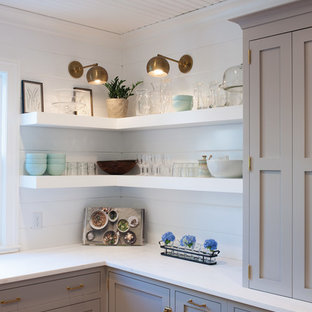 Immagine di una cucina ad U country con ante lisce, ante grigie, paraspruzzi bianco, elettrodomestici in acciaio inossidabile, parquet chiaro e isola