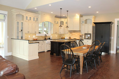 Example of a farmhouse l-shaped medium tone wood floor eat-in kitchen design in Indianapolis with a farmhouse sink, shaker cabinets, distressed cabinets, quartzite countertops, beige backsplash, ceramic backsplash, stainless steel appliances and a peninsula