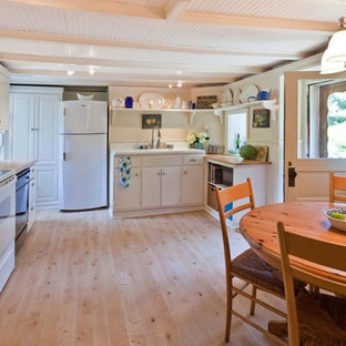Immagine di una cucina country di medie dimensioni con lavello integrato, ante lisce, ante bianche, top in legno, paraspruzzi bianco, elettrodomestici in acciaio inossidabile, pavimento in compensato, paraspruzzi in legno, nessuna isola, pavimento beige e top marrone