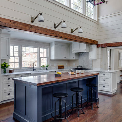 Large farmhouse l-shaped brown floor and medium tone wood floor open concept kitchen photo in Boston with a farmhouse sink, marble countertops, an island, shaker cabinets, blue cabinets, paneled appliances, white countertops, gray backsplash and marble backsplash