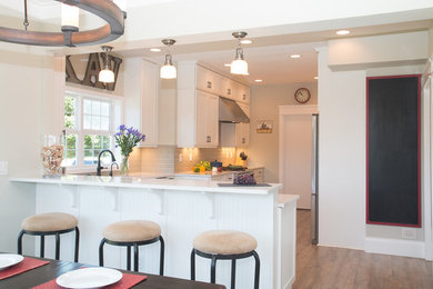 Example of a large farmhouse u-shaped vinyl floor and brown floor enclosed kitchen design in Portland with ceramic backsplash, stainless steel appliances, a peninsula, a farmhouse sink, gray backsplash, louvered cabinets, white cabinets and quartz countertops