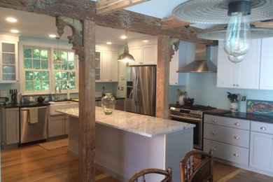 Inspiration for a mid-sized cottage l-shaped medium tone wood floor and brown floor eat-in kitchen remodel in Portland Maine with shaker cabinets, gray cabinets, soapstone countertops, a farmhouse sink, stainless steel appliances, black countertops and an island