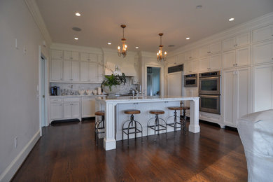 Inspiration for a large transitional l-shaped dark wood floor and brown floor open concept kitchen remodel in Other with an undermount sink, shaker cabinets, white cabinets, marble countertops, white backsplash, marble backsplash, paneled appliances, an island and white countertops