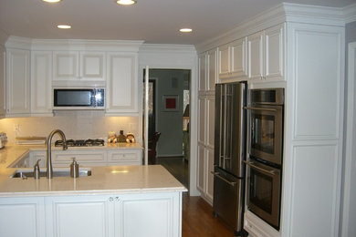 Inspiration för klassiska u-kök, med en undermonterad diskho, luckor med upphöjd panel, vita skåp, rostfria vitvaror och mellanmörkt trägolv
