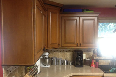 Mid-sized elegant u-shaped laminate floor eat-in kitchen photo in Milwaukee with a double-bowl sink, raised-panel cabinets, brown cabinets, beige backsplash, porcelain backsplash, black appliances and no island