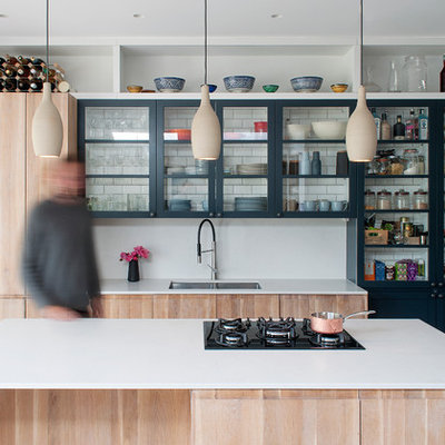 Inspiration for a contemporary galley beige floor kitchen remodel in London with an undermount sink, glass-front cabinets, light wood cabinets, white backsplash, an island and white countertops