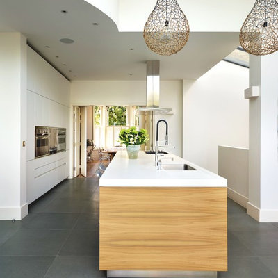 Example of a trendy kitchen design in Oxfordshire with an undermount sink, flat-panel cabinets, white cabinets, stainless steel appliances and an island