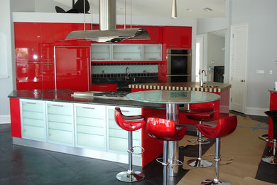 Imagen de cocina comedor actual grande con armarios con paneles lisos, puertas de armario rojas, encimera de esteatita y dos o más islas