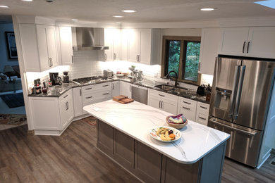 クリーブランドにある高級な中くらいなトランジショナルスタイルのおしゃれなキッチン (アンダーカウンターシンク、落し込みパネル扉のキャビネット、白いキャビネット、珪岩カウンター、白いキッチンパネル、セラミックタイルのキッチンパネル、シルバーの調理設備、無垢フローリング、茶色い床、白いキッチンカウンター) の写真