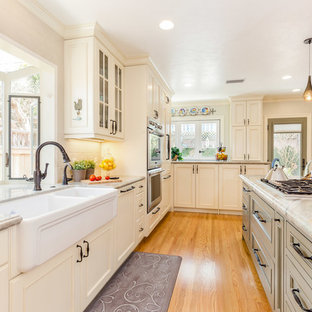 Esempio di una grande cucina chic con lavello stile country, ante con riquadro incassato, ante beige, elettrodomestici in acciaio inossidabile, pavimento in legno massello medio, pavimento arancione, top in quarzo composito e paraspruzzi beige