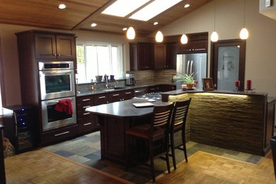 Example of a transitional l-shaped open concept kitchen design in Seattle with an undermount sink, shaker cabinets, dark wood cabinets, granite countertops, gray backsplash and stainless steel appliances