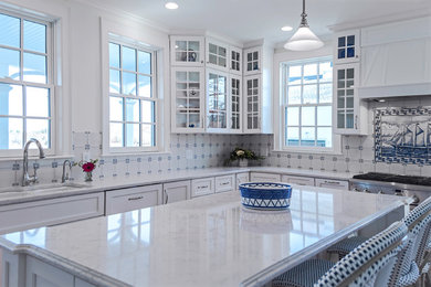 Example of a huge beach style l-shaped medium tone wood floor eat-in kitchen design in Providence with an undermount sink, glass-front cabinets, white cabinets, quartz countertops, white backsplash, ceramic backsplash, stainless steel appliances and an island