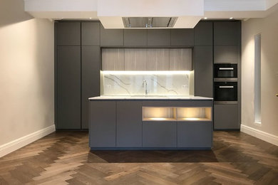 Enclosed kitchen - mid-sized contemporary single-wall enclosed kitchen idea in London with an undermount sink, flat-panel cabinets, gray cabinets, quartzite countertops, white backsplash, travertine backsplash, an island and white countertops