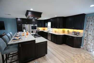 Trendy ceramic tile open concept kitchen photo in New York with an undermount sink, shaker cabinets, dark wood cabinets, granite countertops, beige backsplash, stone tile backsplash, stainless steel appliances, an island and white countertops