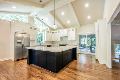 Example of a large trendy l-shaped medium tone wood floor and brown floor eat-in kitchen design in Atlanta with an undermount sink, shaker cabinets, white cabinets, quartz countertops, white backsplash, ceramic backsplash, stainless steel appliances, an island and white countertops