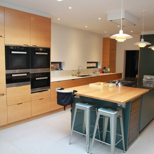 Design ideas for a large contemporary single-wall kitchen/diner in London with flat-panel cabinets, light wood cabinets, stainless steel appliances, an island, a submerged sink, wood worktops, grey floors and brown worktops.