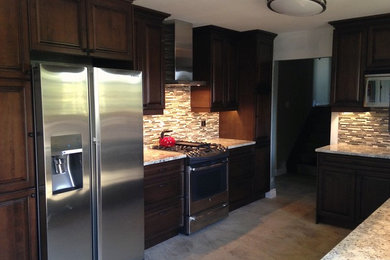 Example of a mid-sized classic u-shaped eat-in kitchen design in Toronto with dark wood cabinets, granite countertops, multicolored backsplash, ceramic backsplash, stainless steel appliances, no island and raised-panel cabinets
