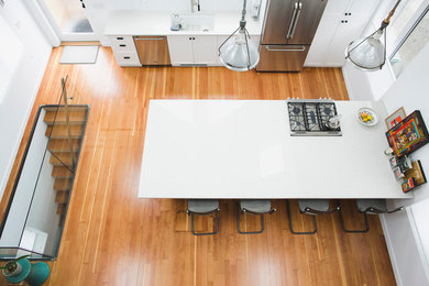 Moderne Wohnküche mit Unterbauwaschbecken, Schrankfronten im Shaker-Stil, weißen Schränken, Quarzit-Arbeitsplatte, Küchenrückwand in Weiß, Küchengeräten aus Edelstahl, hellem Holzboden und Halbinsel in Vancouver