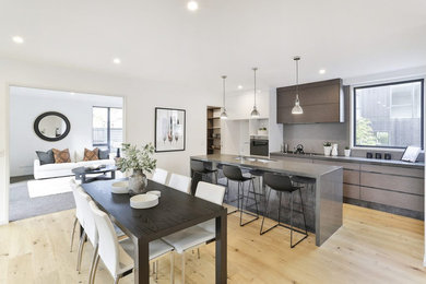 Zweizeilige, Mittelgroße Moderne Wohnküche mit integriertem Waschbecken, Granit-Arbeitsplatte, Küchenrückwand in Grau, Küchengeräten aus Edelstahl, braunem Holzboden, Kücheninsel und bunter Arbeitsplatte in Auckland