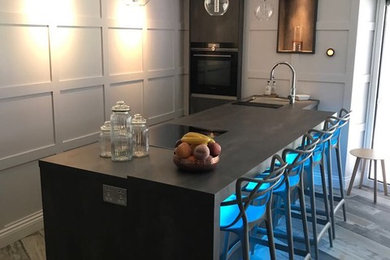 マンチェスターにある高級な中くらいなコンテンポラリースタイルのおしゃれなキッチン (グレーのキャビネット、黒い調理設備、ラミネートの床、グレーの床) の写真