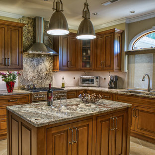 Réalisation d'une cuisine américaine tradition en U de taille moyenne avec un évier 3 bacs, un placard avec porte à panneau surélevé, des portes de placard marrons, un plan de travail en granite, une crédence beige, une crédence en carreau de céramique, un électroménager en acier inoxydable, un sol en carrelage de céramique et un îlot central.