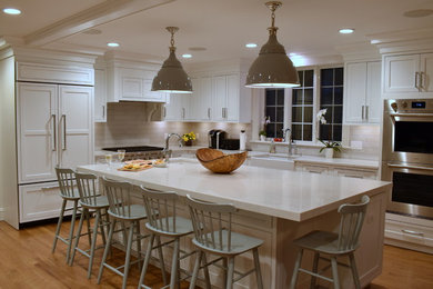 Large transitional l-shaped medium tone wood floor eat-in kitchen photo in Boston with an undermount sink, recessed-panel cabinets, white cabinets, quartz countertops, white backsplash, ceramic backsplash, paneled appliances, an island and gray countertops