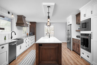 Inspiration for a transitional galley light wood floor and brown floor enclosed kitchen remodel in Toronto with a farmhouse sink, shaker cabinets, white cabinets, quartzite countertops, white backsplash, subway tile backsplash, stainless steel appliances, an island and white countertops