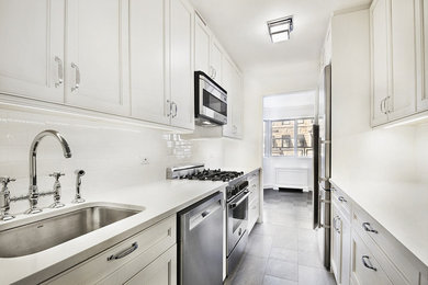 Small transitional galley slate floor and gray floor enclosed kitchen photo in New York with an undermount sink, recessed-panel cabinets, white cabinets, quartzite countertops, white backsplash, subway tile backsplash, stainless steel appliances and no island