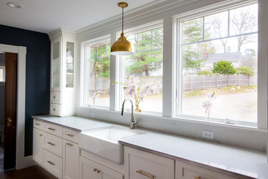 Enclosed kitchen - large transitional l-shaped enclosed kitchen idea in Boston with a farmhouse sink, shaker cabinets, white cabinets, quartz countertops, white backsplash, stainless steel appliances, an island and white countertops