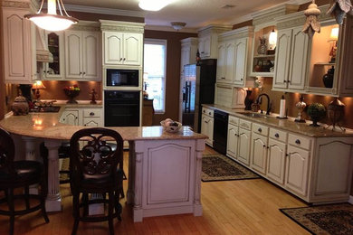 Eat-in kitchen - mid-sized traditional u-shaped light wood floor and beige floor eat-in kitchen idea in Atlanta with an undermount sink, raised-panel cabinets, white cabinets, granite countertops, black appliances and a peninsula