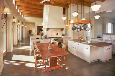 Example of a large classic l-shaped concrete floor eat-in kitchen design in Phoenix with an undermount sink, shaker cabinets, white cabinets, granite countertops, white backsplash, ceramic backsplash, stainless steel appliances and an island