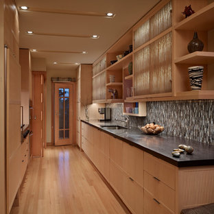 Design ideas for a small modern galley kitchen pantry in Seattle with an undermount sink, light wood cabinets, limestone benchtops, panelled appliances, light hardwood floors and no island.
