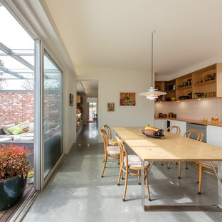 This is an example of a small contemporary single-wall eat-in kitchen in Canberra - Queanbeyan with a single-bowl sink, white cabinets, laminate benchtops, white splashback, ceramic splashback, stainless steel appliances, concrete floors, no island, grey floor and orange benchtop.
