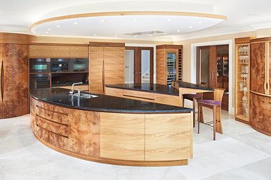 Cette image montre une grande cuisine américaine design avec un évier encastré, un plan de travail en granite, un électroménager noir et 2 îlots.