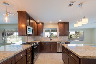 Large trendy l-shaped porcelain tile and beige floor eat-in kitchen photo in Los Angeles with an undermount sink, shaker cabinets, medium tone wood cabinets, granite countertops, beige backsplash, stone tile backsplash, stainless steel appliances, an island and multicolored countertops