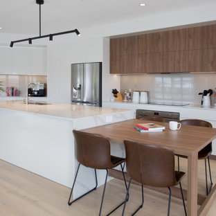 Inspiration for a large contemporary galley eat-in kitchen in Gold Coast - Tweed with an undermount sink, quartz benchtops, glass sheet splashback, stainless steel appliances, light hardwood floors, with island, brown floor, white benchtop, flat-panel cabinets, white cabinets and beige splashback.